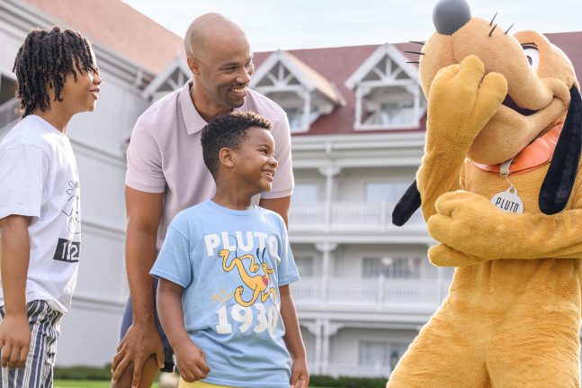A family smiles with Pluto at Disney's Grand Floridian Resort