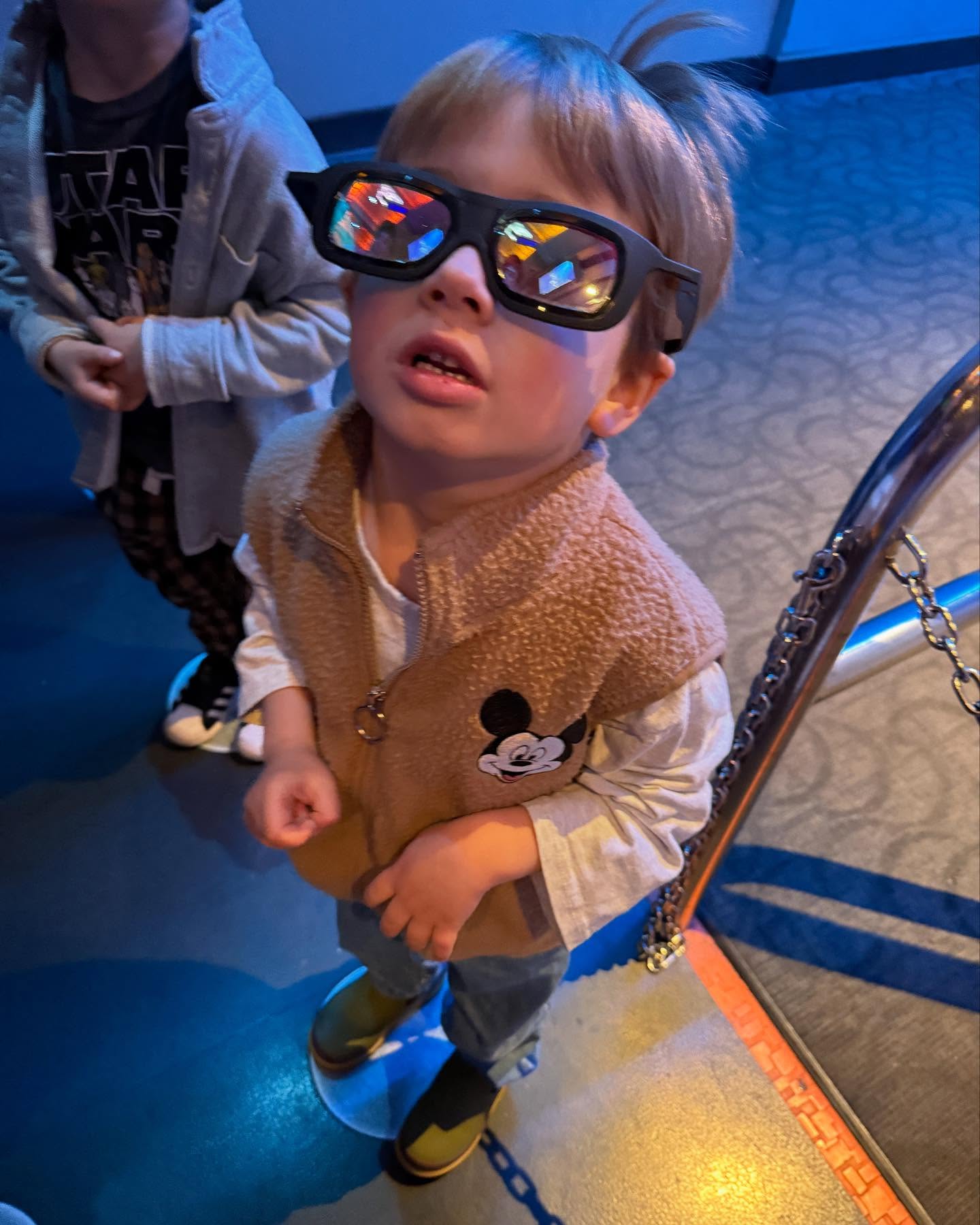 Mandy Moore's son at Disney with 3D glasses and a Mickey vest.