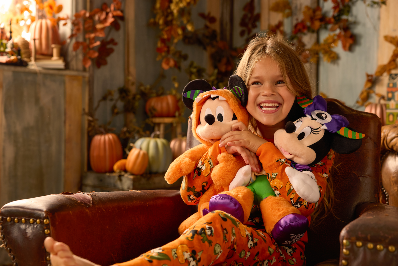 Young girl holding Mickey Mouse Family Halloween plushes