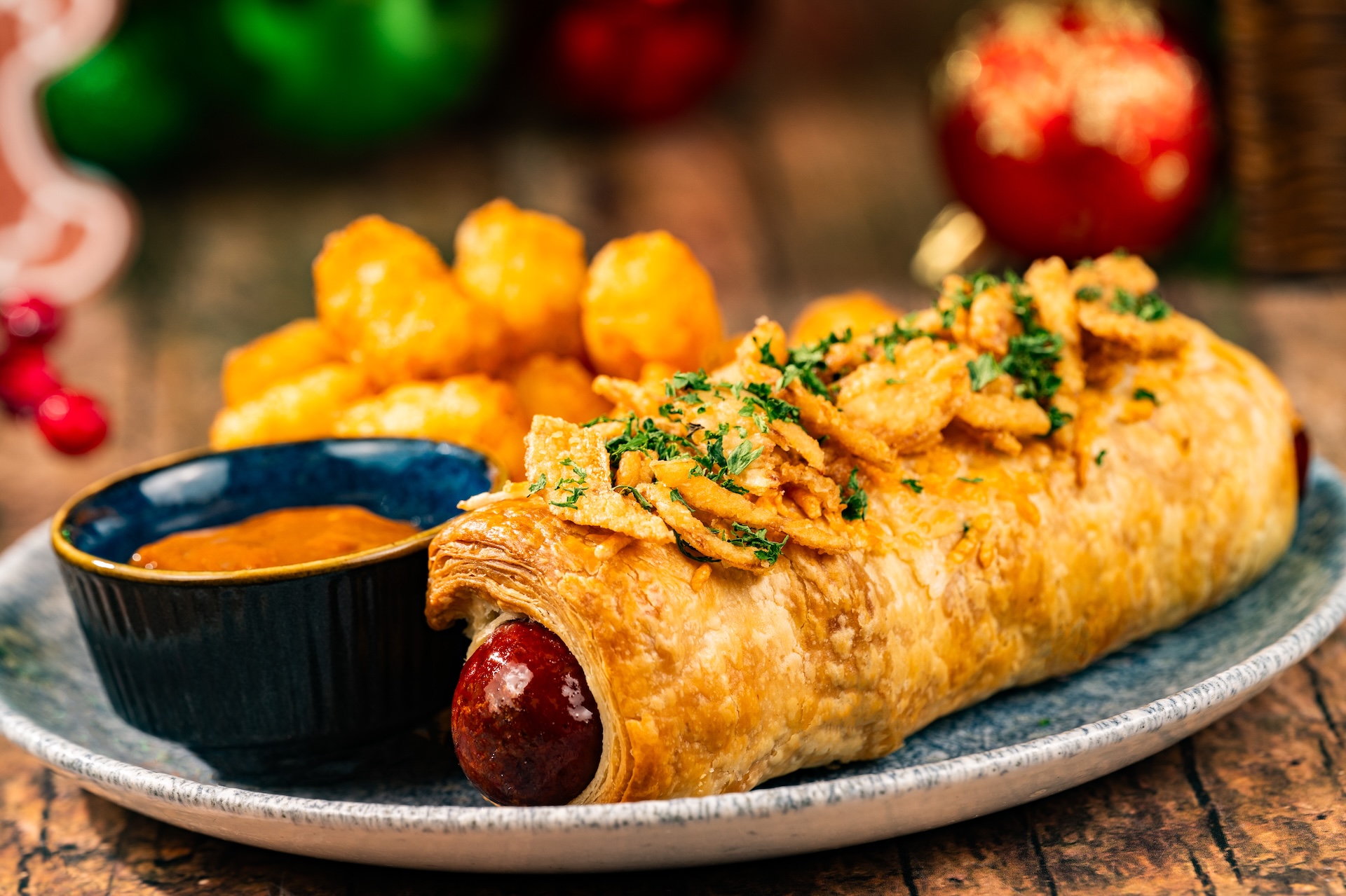 Pig in a Blanket: Parmesan puff pastry-wrapped all-beef hot dog, crispy onions, and honey mustard barbecue sauce served with tots