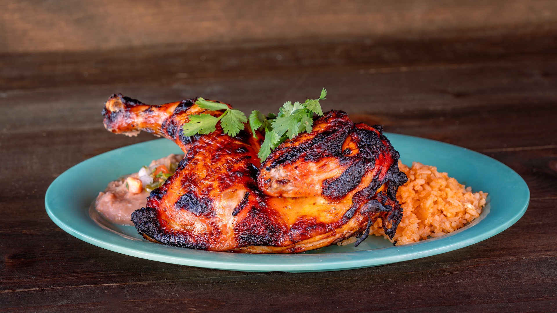 Achiote Half Chicken: Roasted achiote-marinated chicken served with Spanish rice, refried beans, and nopal salad