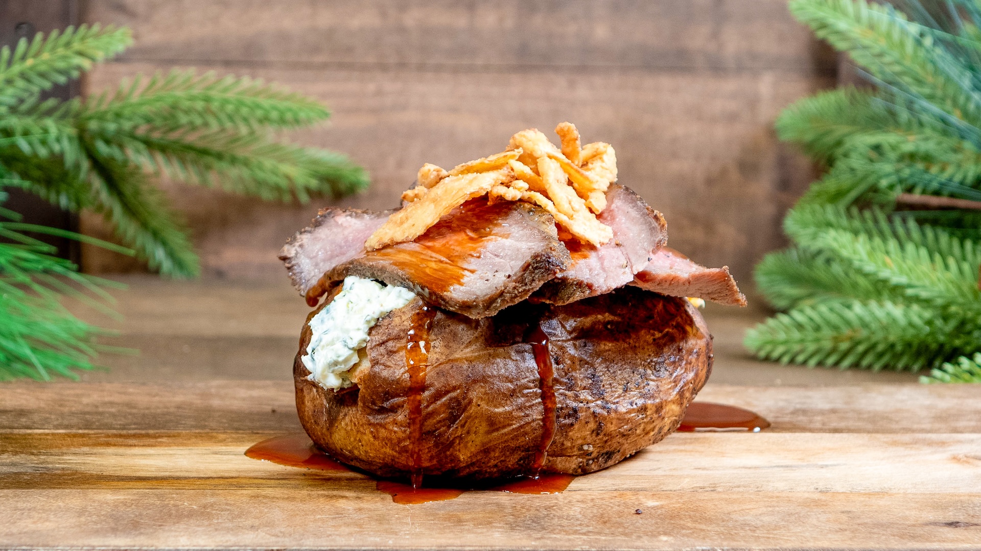 Holiday Beef Dinner Potato: Sliced tri-tip steak, spinach artichoke dip, demi-glace, and crispy onions 