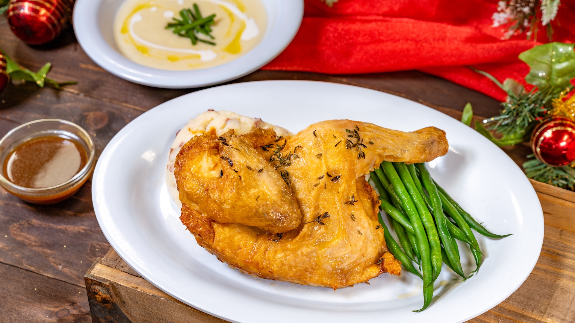 Adult Menu: Holiday meal offering a creamy potato leek soup garnished with fried leeks, chives, and citrus cream, herb-roasted chicken entrée with mashed potatoes, and buttered haricots verts with a caramelized onion sauce, served with a holiday Yule log dessert and adult fountain beverage  