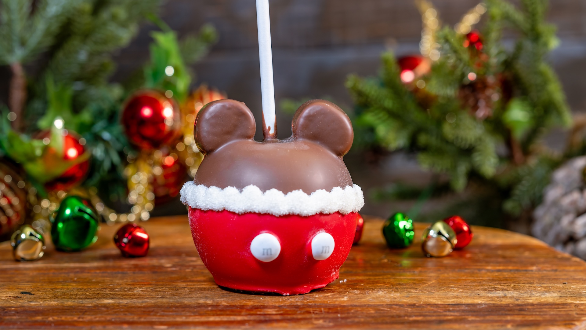 Santa Mickey Caramel Apple: Green apple dipped in caramel with two marshmallow ears, dipped in milk chocolate, and decorated with red-colored white chocolate, white sanding sugar, and white M&M’S Milk Chocolate Candies (New) 
