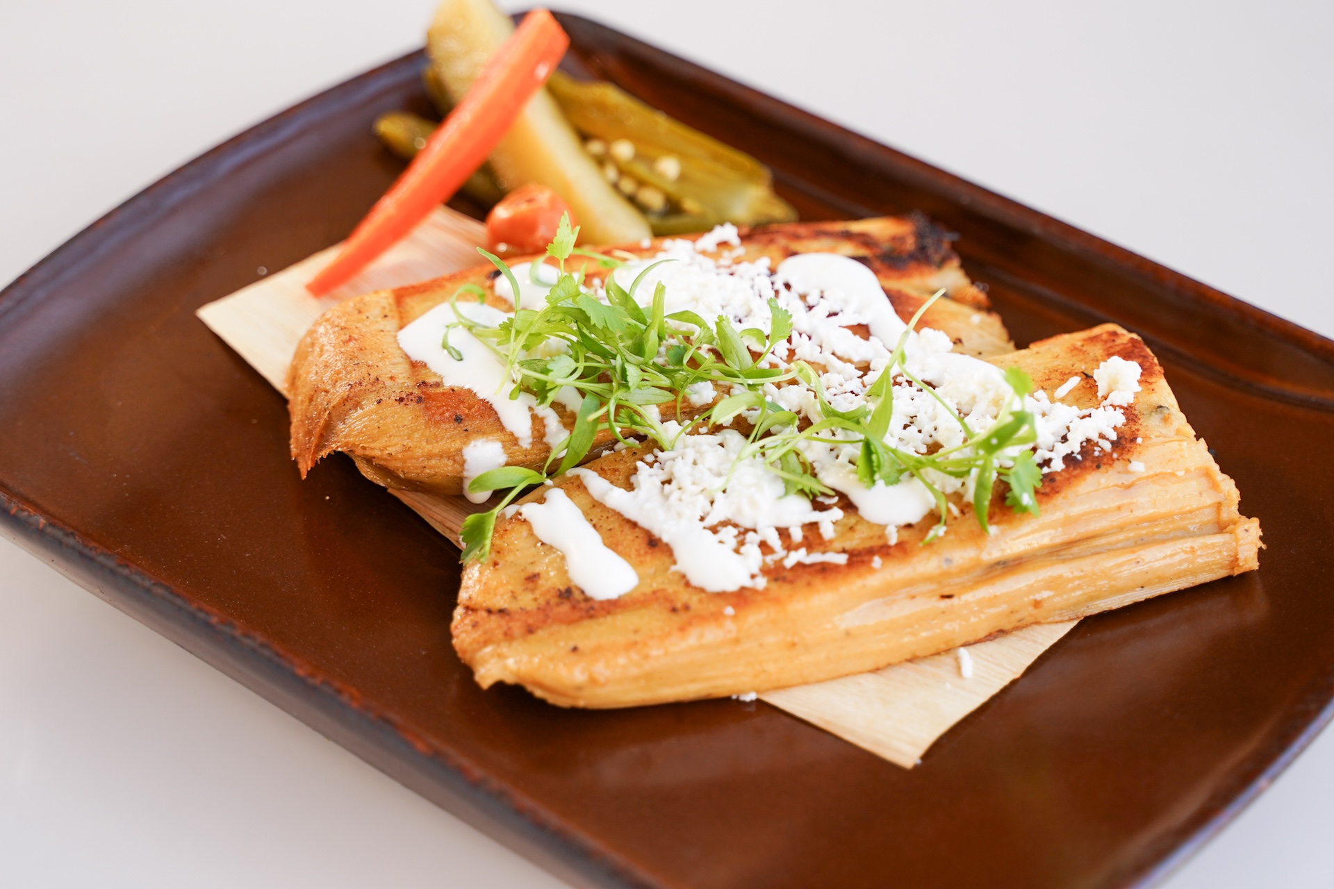 Tamal de Rajas: Corn husk tamal, rajas, Mexican cheese blend, and pickled jalapeños, carrots and squash veggies (New) 