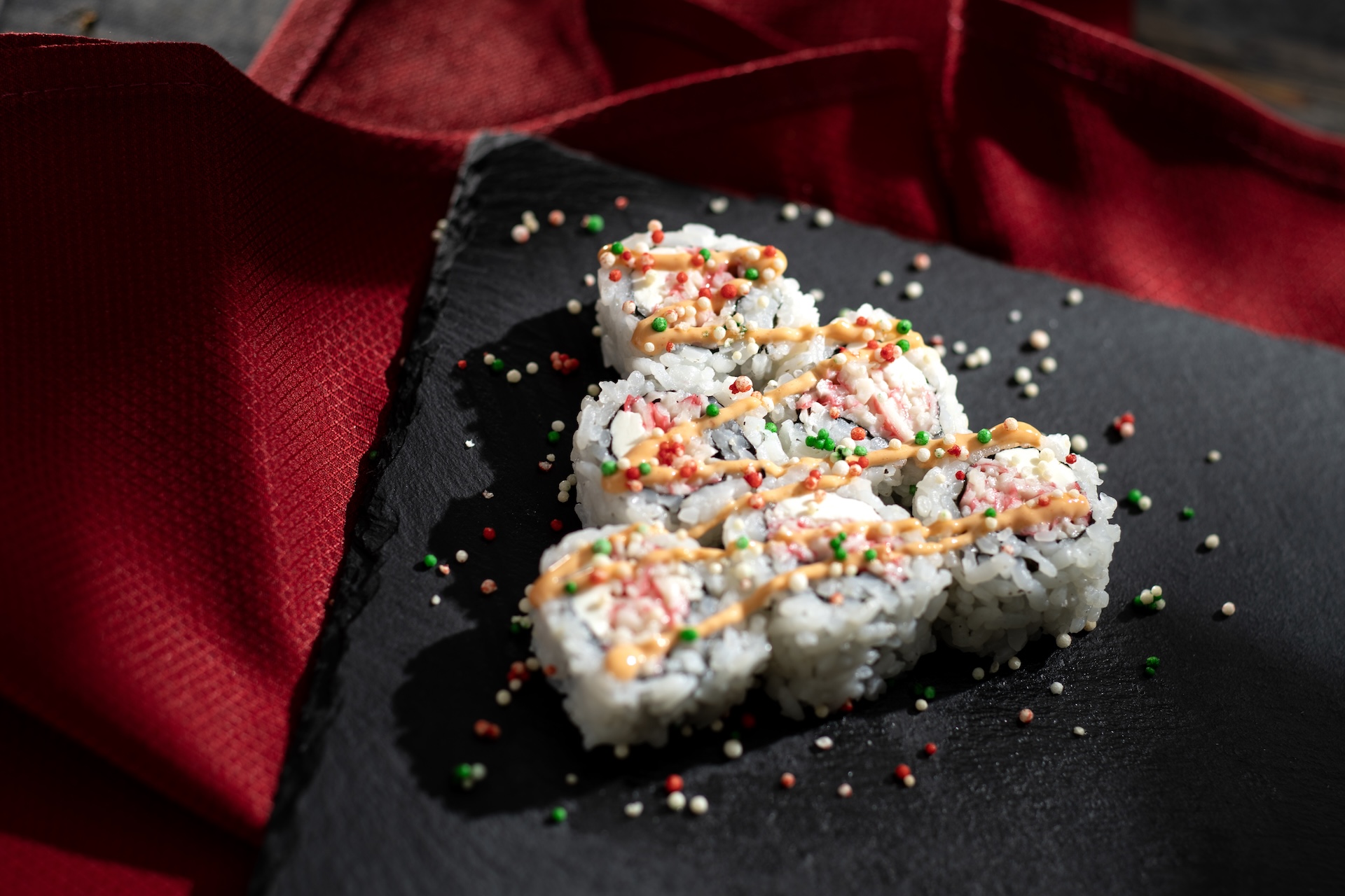 Sushi Tree Roll: Christmas tree-shaped sushi roll with krab meat and cream cheese garnished with spicy mayo and colorful rice pearls