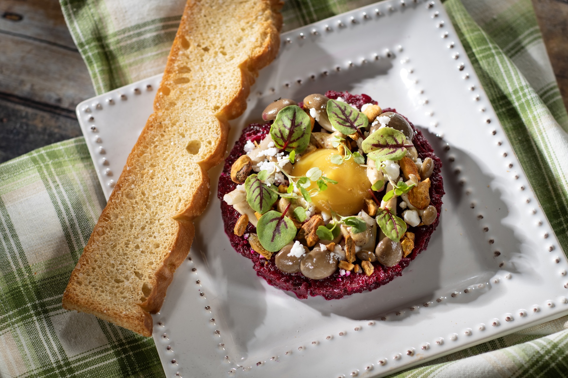 Citrus-braised Beet Tartare with golden beet “egg yolk,” mustard vinaigrette, pickled mustard seeds, pickled mushrooms, spiced pistachios, and “feta” snow (Plant-based)