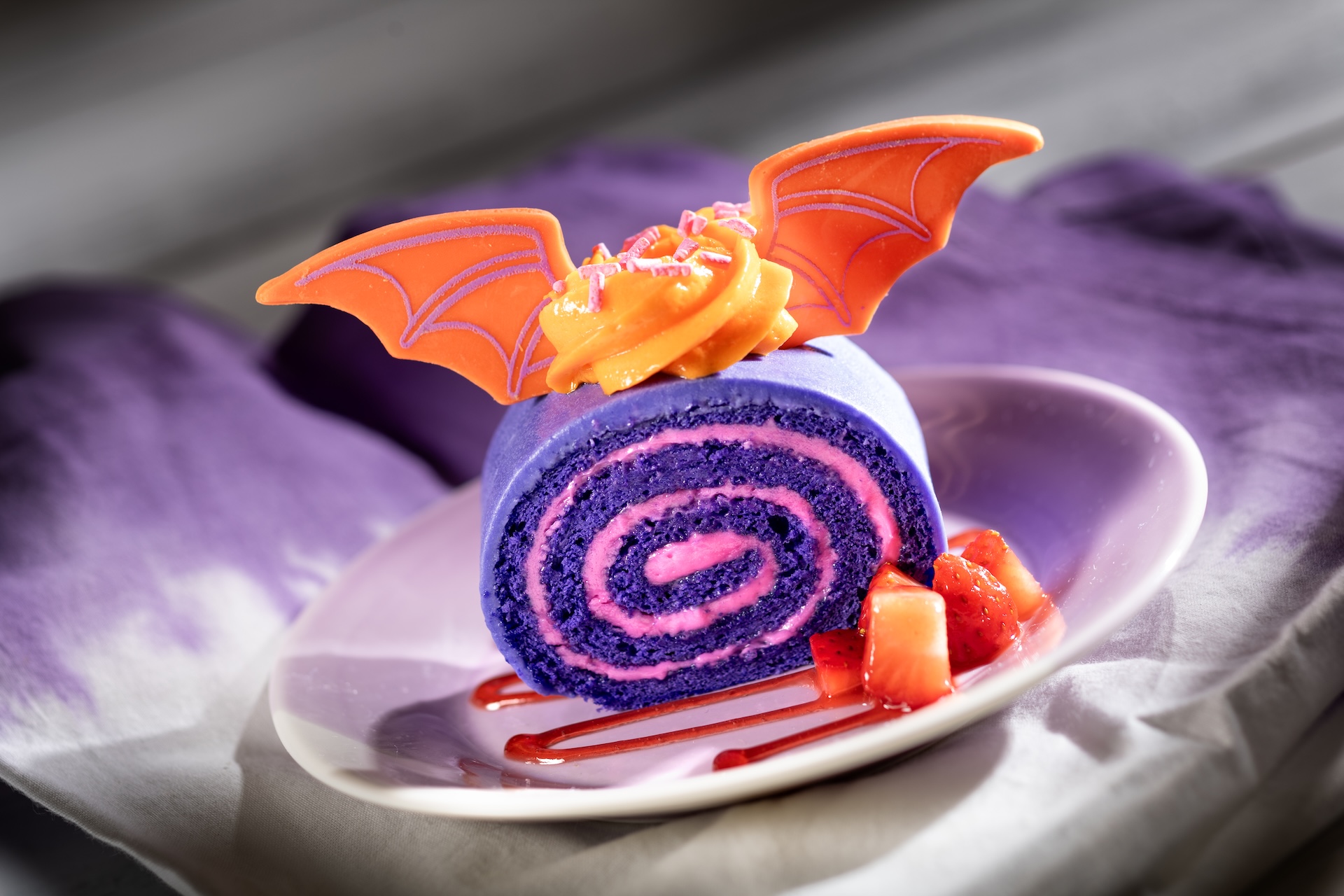 Figment Fantasy Cake: Sponge cake filled with strawberry whipped cream topped with a white chocolate ganache, orange icing, and white chocolate Figment wings (New)